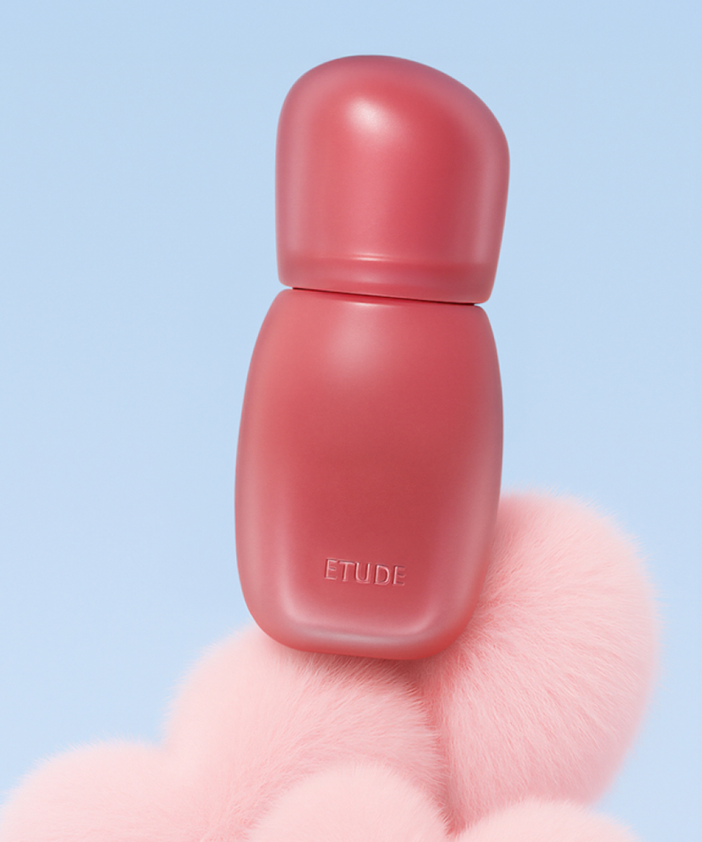 ETUDE Cozy Fixing Tint 4g de ETUDE, tube rosé sur fond bleu ciel, posé sur un accessoire duveteux rose.