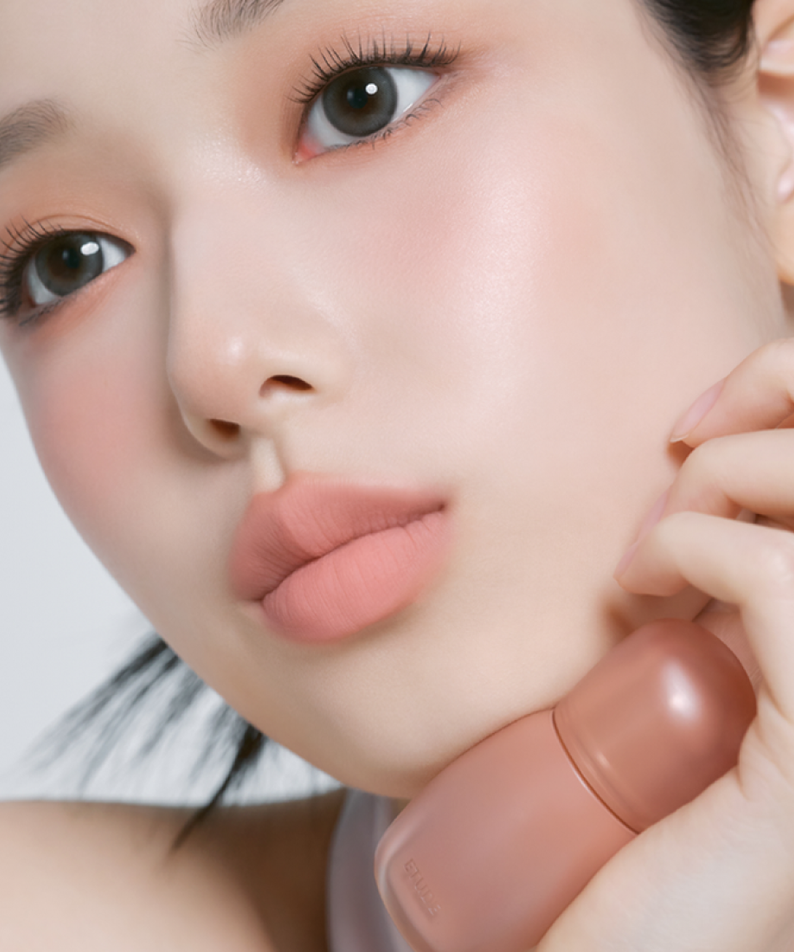 Décris l'image en français : ETUDE  Cozy Fixing Tint 4g de la marque ETUDE, sur visage maquillé aux lèvres roses.