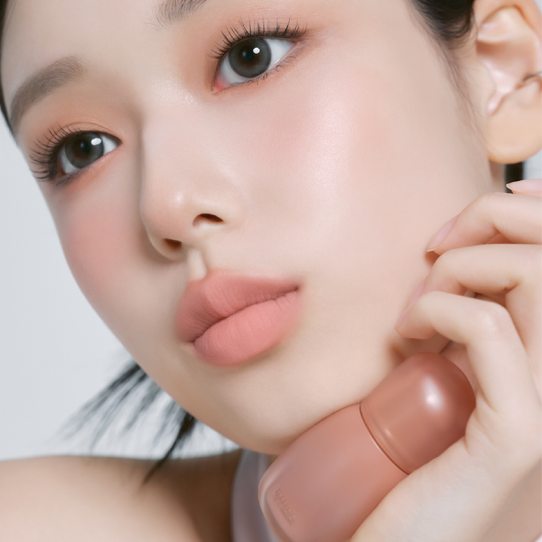 Décris l'image en français : ETUDE  Cozy Fixing Tint 4g de la marque ETUDE, sur visage maquillé aux lèvres roses.