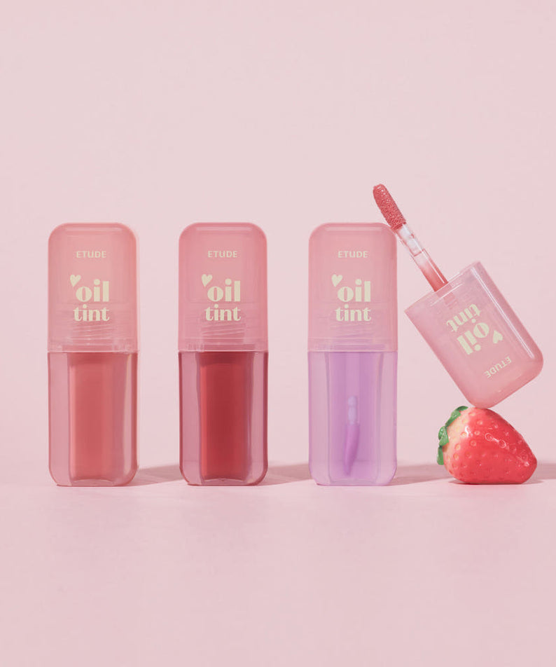 ETUDE Dear Darling Oil Tint, flacons et applicateur avec teintes rosées sur fond rose, visuel produit maquillage.