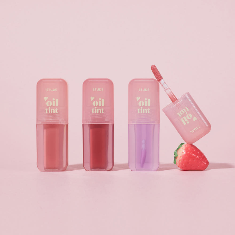 ETUDE Dear Darling Oil Tint, flacons et applicateur avec teintes rosées sur fond rose, visuel produit maquillage.