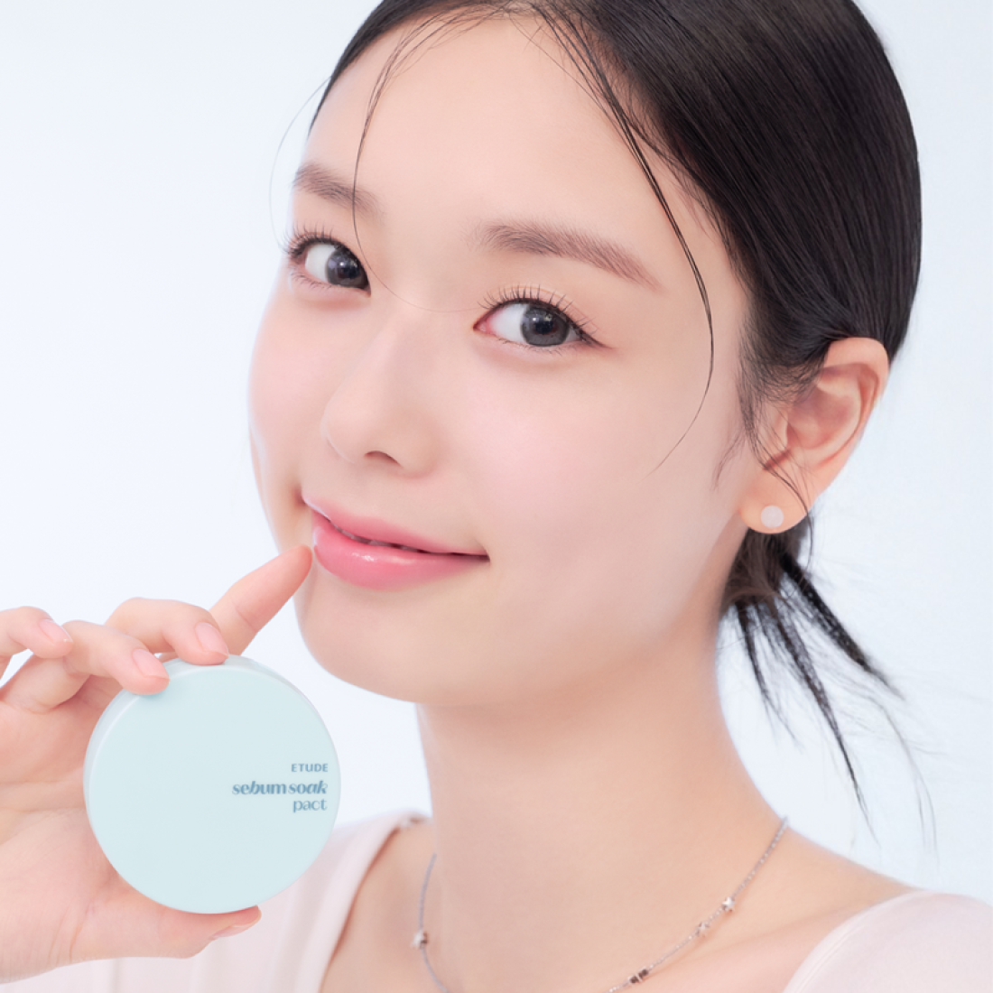 ETUDE  Fiji Ssok Pact 9.5g : une femme tient le compact rond bleu pâle, portrait beauté sur fond clair.