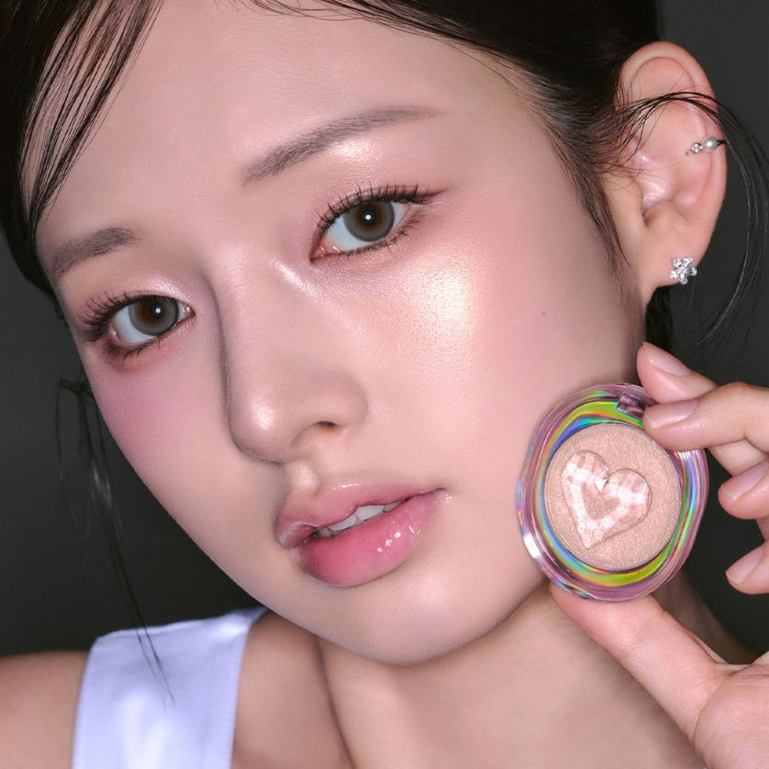 ETUDE Shooting Beam Highlighter 3g de la marque ETUDE, sur peau maquillée; visage en gros plan tenant le produit.