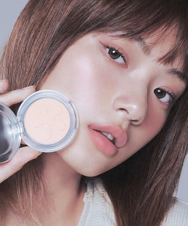 Femme tenant ETUDE Face Brightener, produit cosmétique pour illuminer le teint, maquillage naturel et lumineux, beauté éclatante.