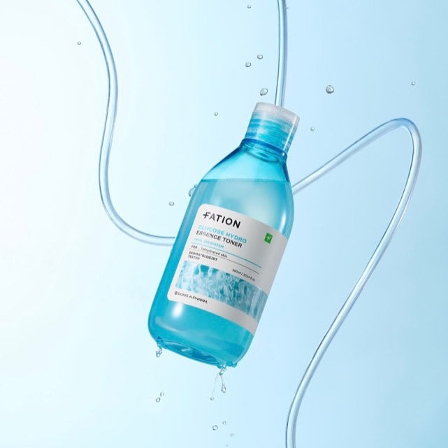 FATION Glucose Hydro Essence Toner 500ml, bouteille FATION sur fond bleu avec gouttes d’eau et éclaboussures.