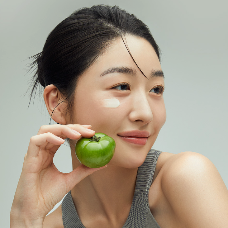 FULLY Green Tomato Cream Tube 90ml, crème anti-imperfections FULLY, sur tube, visage d’une femme avec tomate verte en arrière-plan.