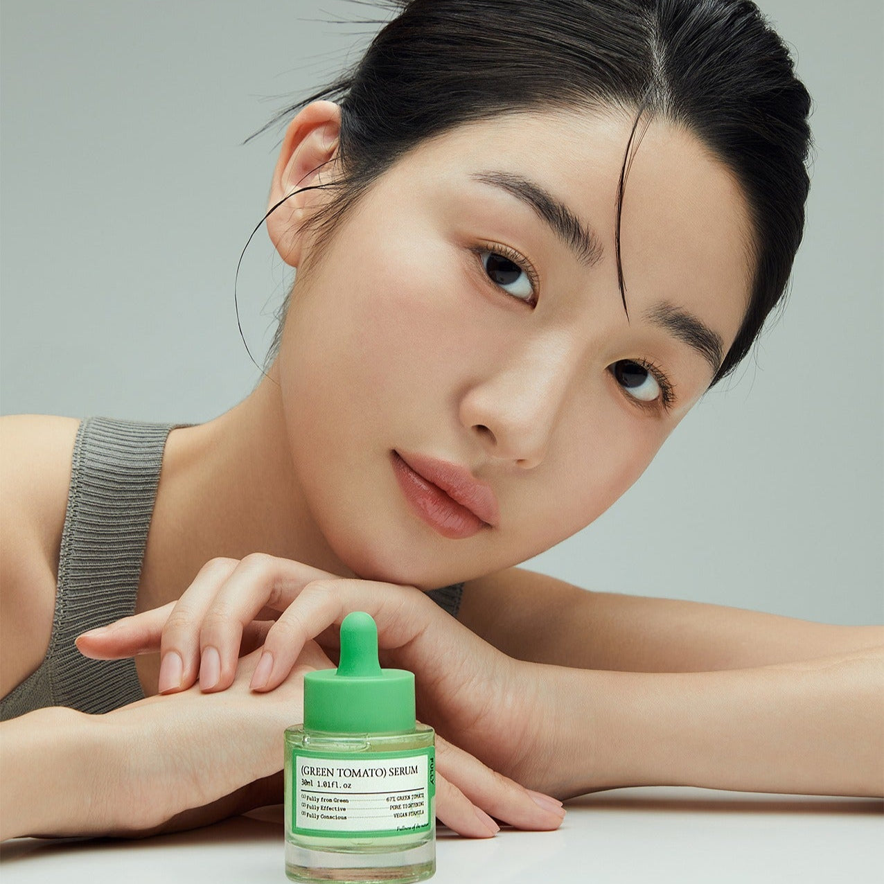 FULLY  Green Tomato Serum 30ml, flacon vert sur table près d’une femme visage maquillé, soin visage FULLY