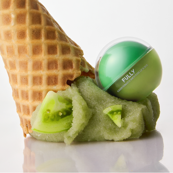 FULLY Green Tomato Smoothie Lip Scrub 12g de FULLY, baume vert en contexte de gaufrette et tomates, visuel produit.