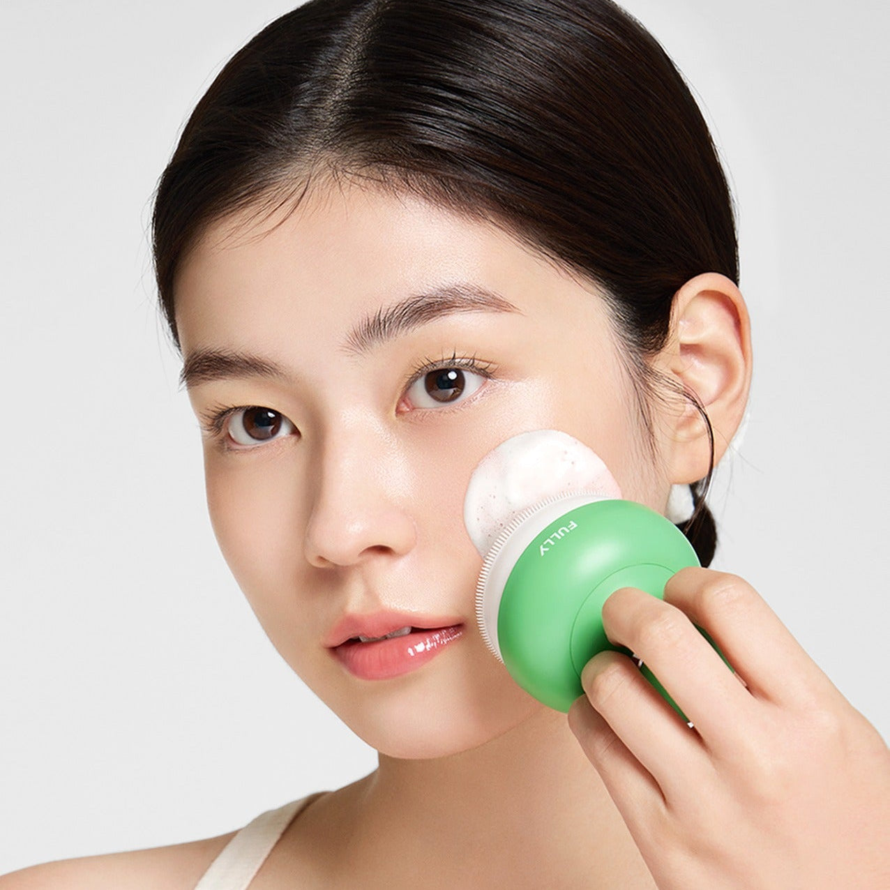 FULLY  Pore brush, visage en gros plan utilisant la brosse pour nettoyer les pores, marque FULLY, fond clair.