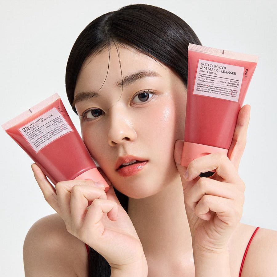 Décris l'image en français : FULLY  Red Tomato Jam Pack Cleanser 120ml, femme montre le tube rouge de la marque, fond clair.