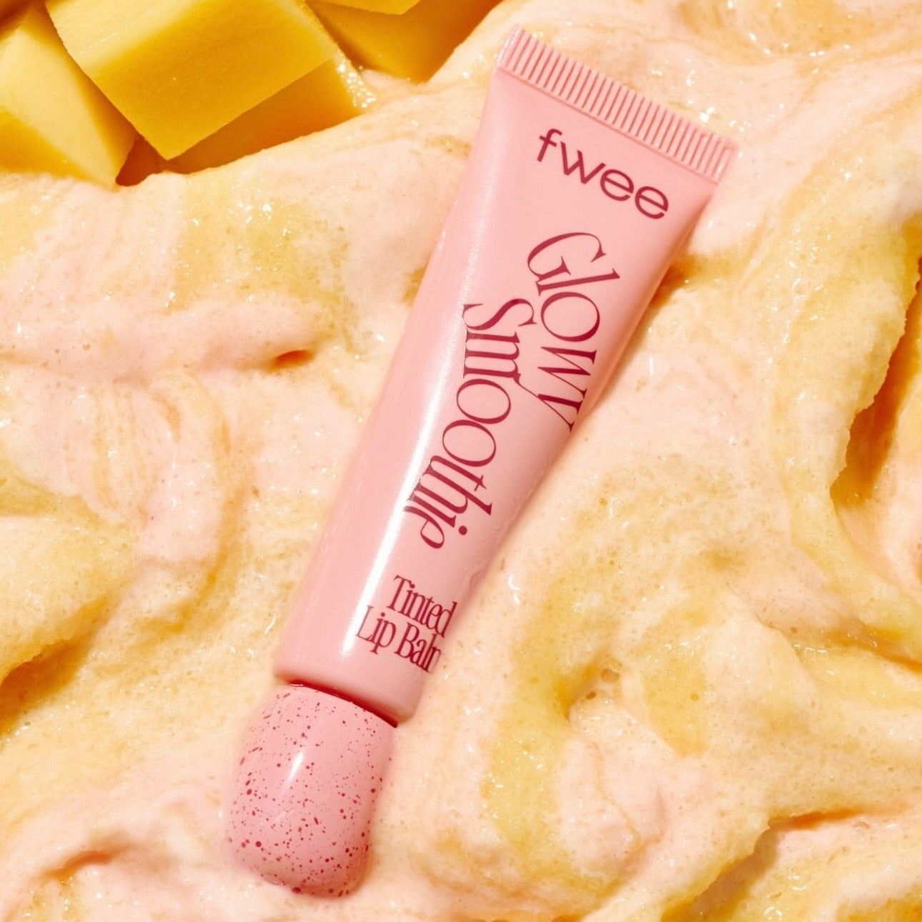 FWEE Glow Smoothie Tinted Lip Balm de la marque FWEE, tube rose sur smoothie crème, ambiance gourmande.
