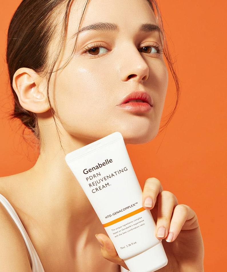 Femme tenant un tube de GENABELLE PDRN Rejuvenating Cream 70ml, crème régénérante sur fond orange.