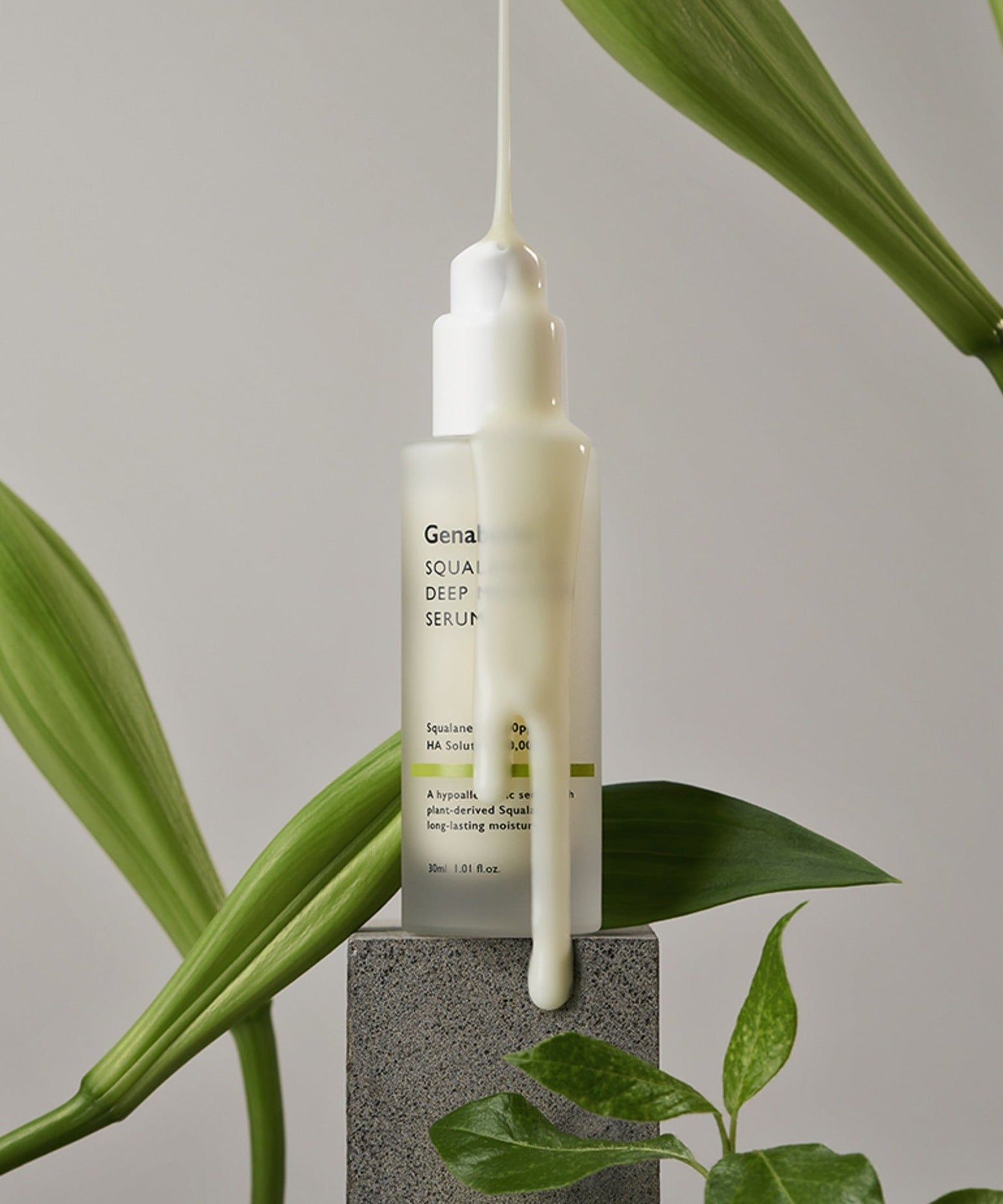 GENABELLE Squalane 53 Deep Moisture Serum 30ml en train de couler sur un bloc, entouré de feuilles vertes élégantes.