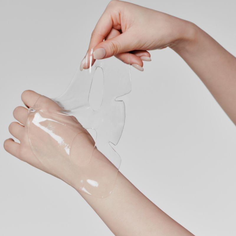 GLOW Aloe Hydrogel Mask Pack 3ea de la marque GLOW sur des mains avec masque hydrogel transparent, fond clair