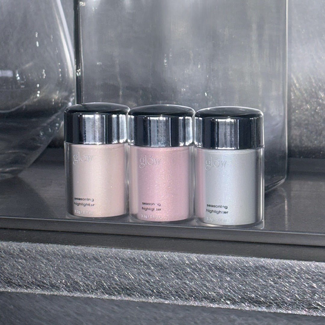 GLOW Seasoning Highlighter de la marque Glow, pots colorés rose et argent sur plateau vitré en boutique