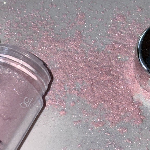 GLOW Seasoning Highlighter de la marque, sur fond pailleté rose et noir, ambiance maquillage scintillante