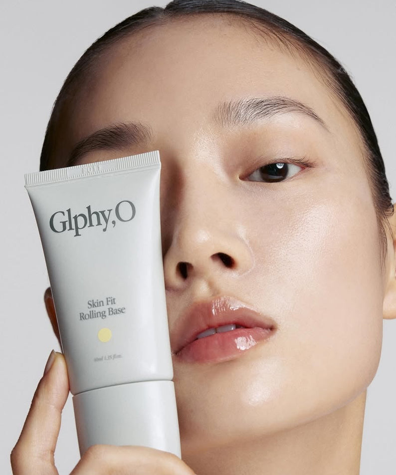 GLPHYO Skin Fit Rolling Base 40ml de GlphyO : tube de base tenu par une femme, peau lumineuse en studio