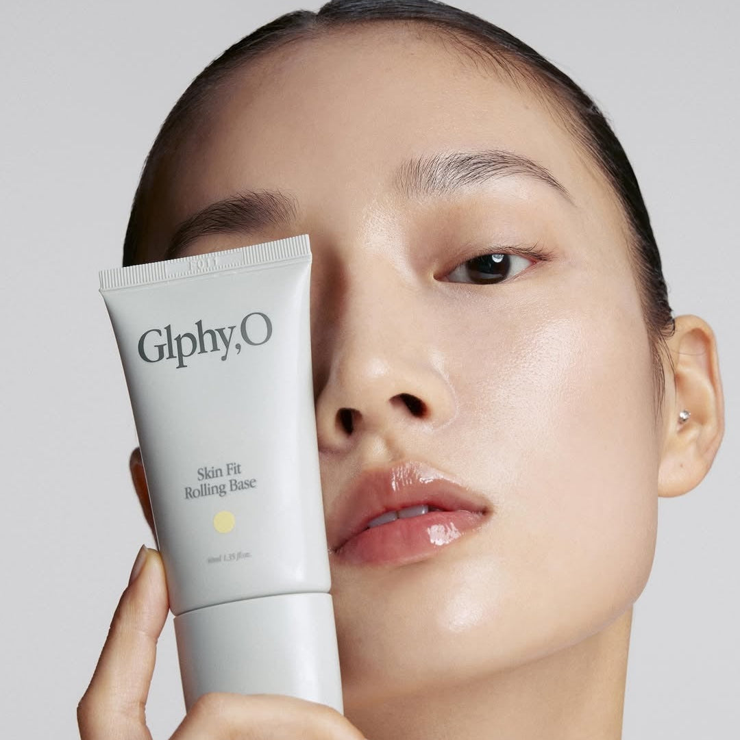 GLPHYO Skin Fit Rolling Base 40ml de GlphyO : tube de base tenu par une femme, peau lumineuse en studio
