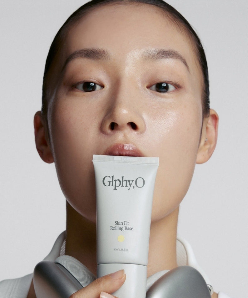 Décris l'image en français : GLPHYO Skin Fit Rolling Base 40ml de GlphyO, tube crème tenu sur fond clair, visage maquillé