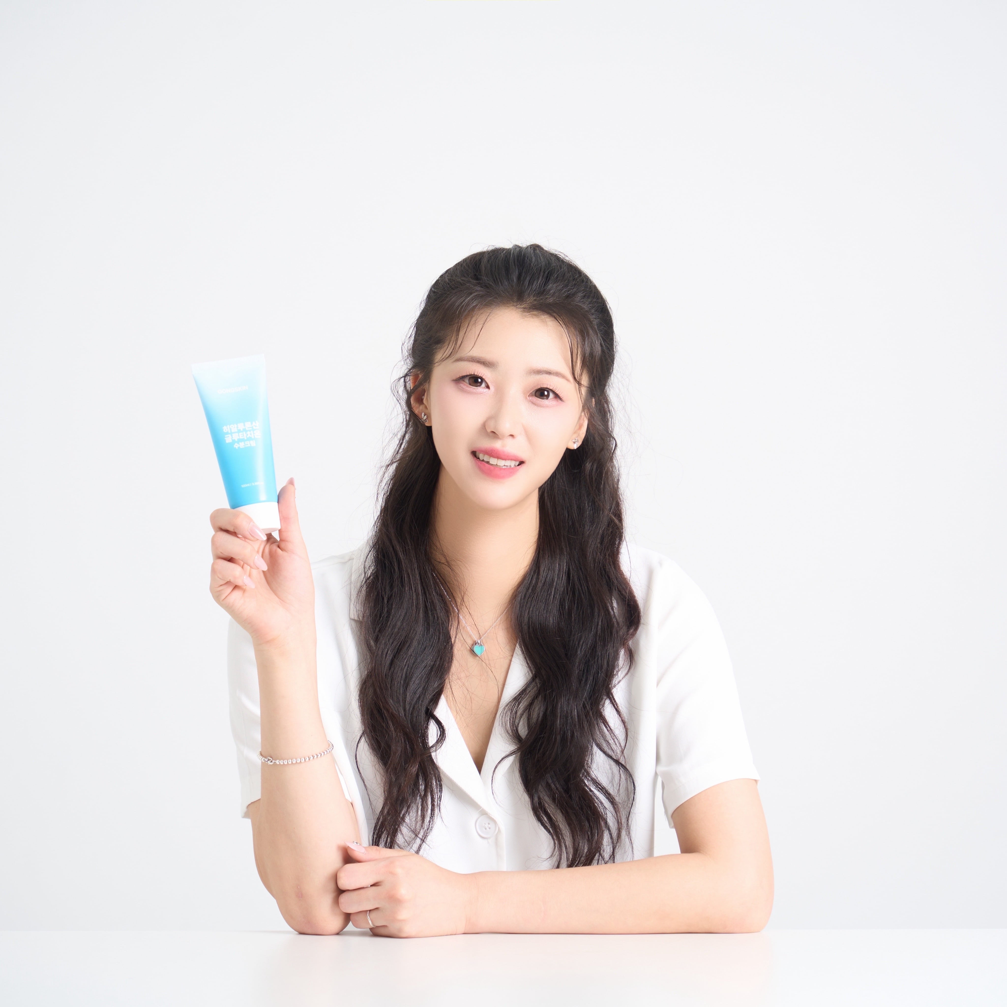 GONGSKIN Hyaluronic Acid Glutathione Moisturizing Cream 100ml, femme en studio tenant le tube bleu sur fond clair.