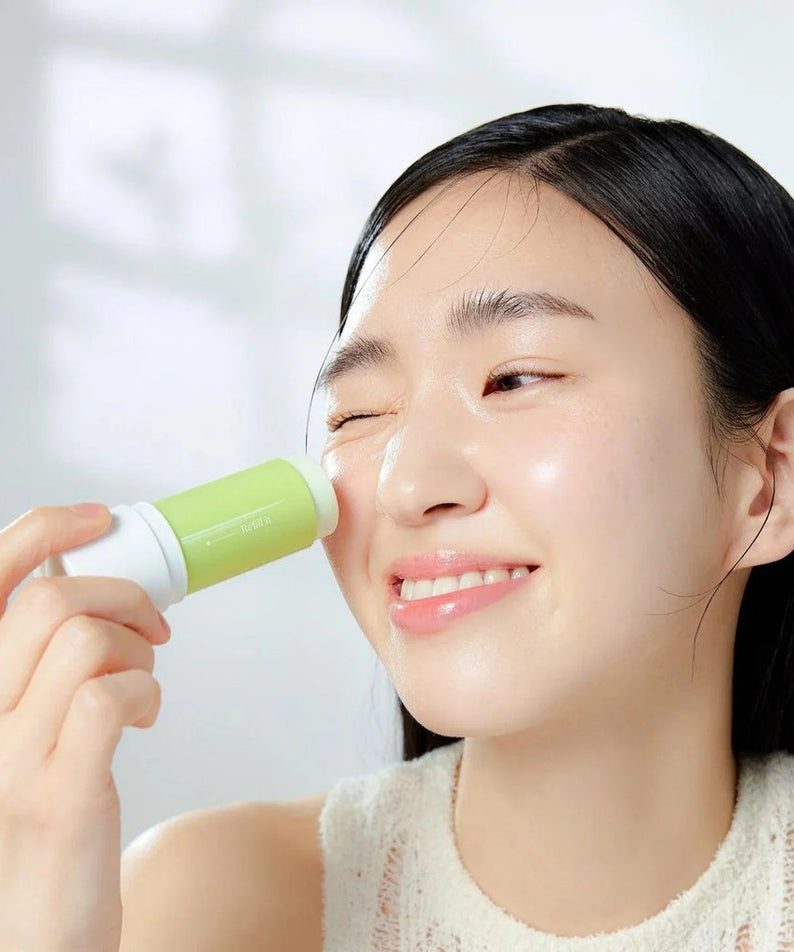 Femme souriante appliquant GOODAL Clear Eoseongcho Soothing Cooling Sun Stick sur le visage, protection solaire rafraîchissante en bâton.