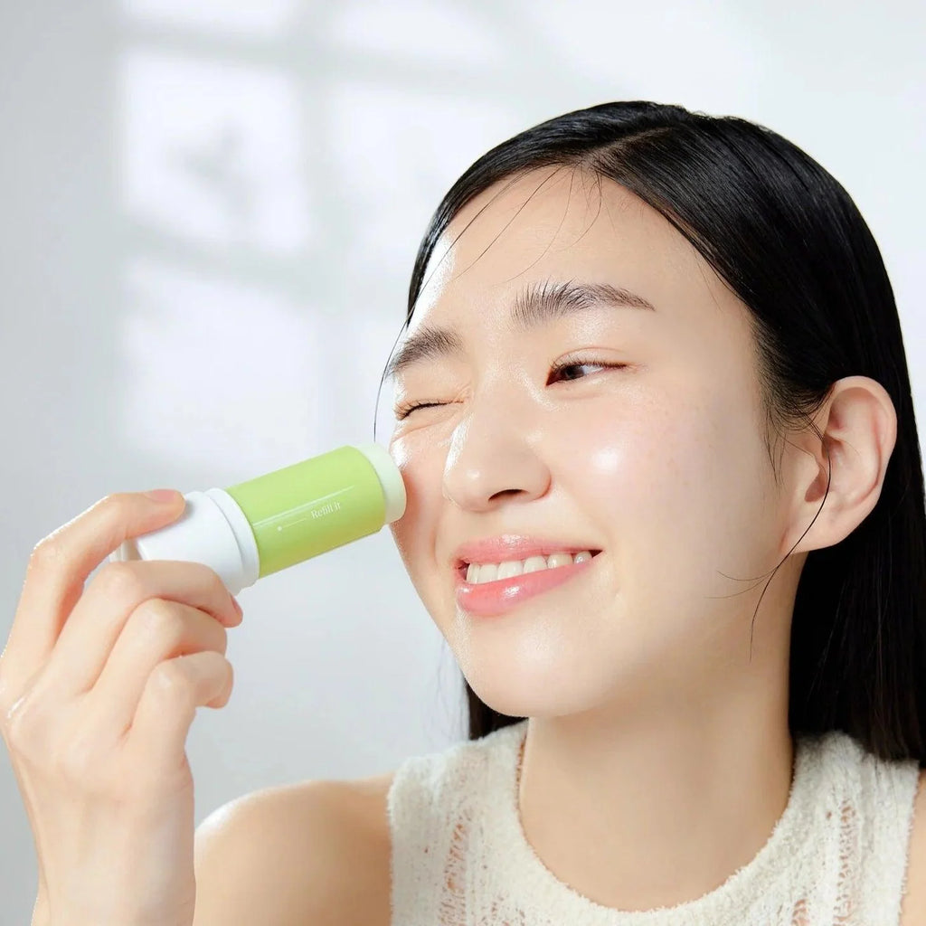 Femme souriante appliquant GOODAL Clear Eoseongcho Soothing Cooling Sun Stick sur le visage, protection solaire rafraîchissante en bâton.