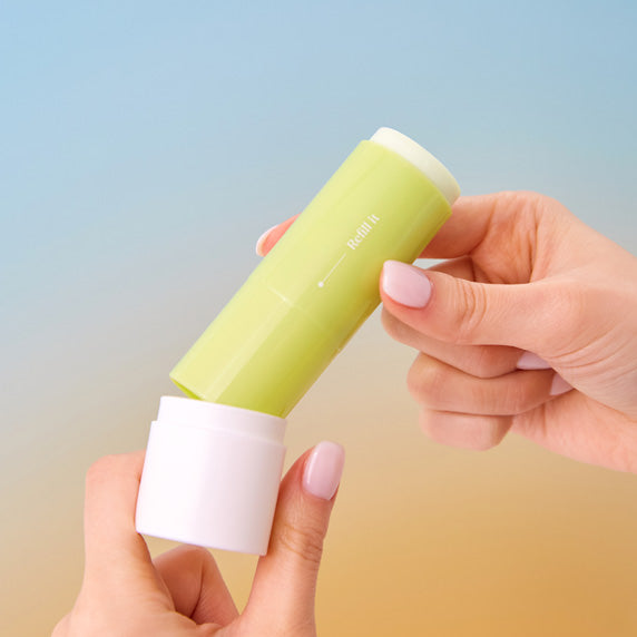Personne tenant un GOODAL Clear Eoseongcho Soothing Cooling Sun Stick au-dessus d'un fond dégradé bleu et orange.