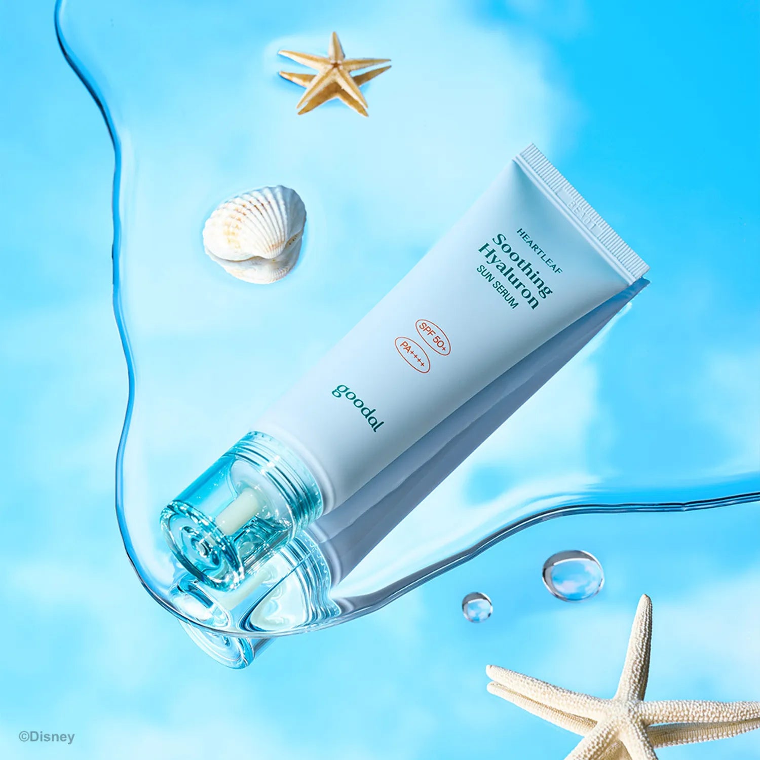 Décris l'image en français: GOODAL Eoseongcho Hyaluronic Acid Sun Serum 50ml, tube Goodal sur fond bleu, coquillages et étoile de mer.