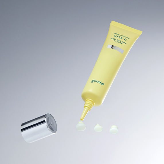 GOODAL Green Tangerine Vita C Dark Circle Eye Cream de Goodal, tube jaune appliqué avec gouttes sur fond clair.
