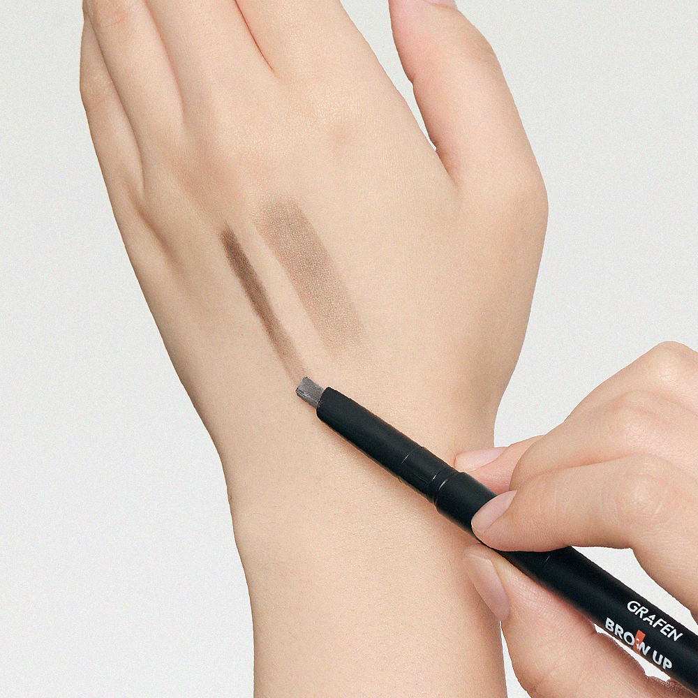 Main tenant GRAFEN Brow Up Brow Pencil 0.3g, dessin de sourcils sur peau, fond clair, gros plan produit maquillage