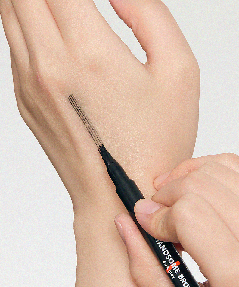 Décris l'image en français : GRAFEN  Handsome Tattoo Brow 0.8g, stylo tatouage sourcils sur la main, application visuelle.