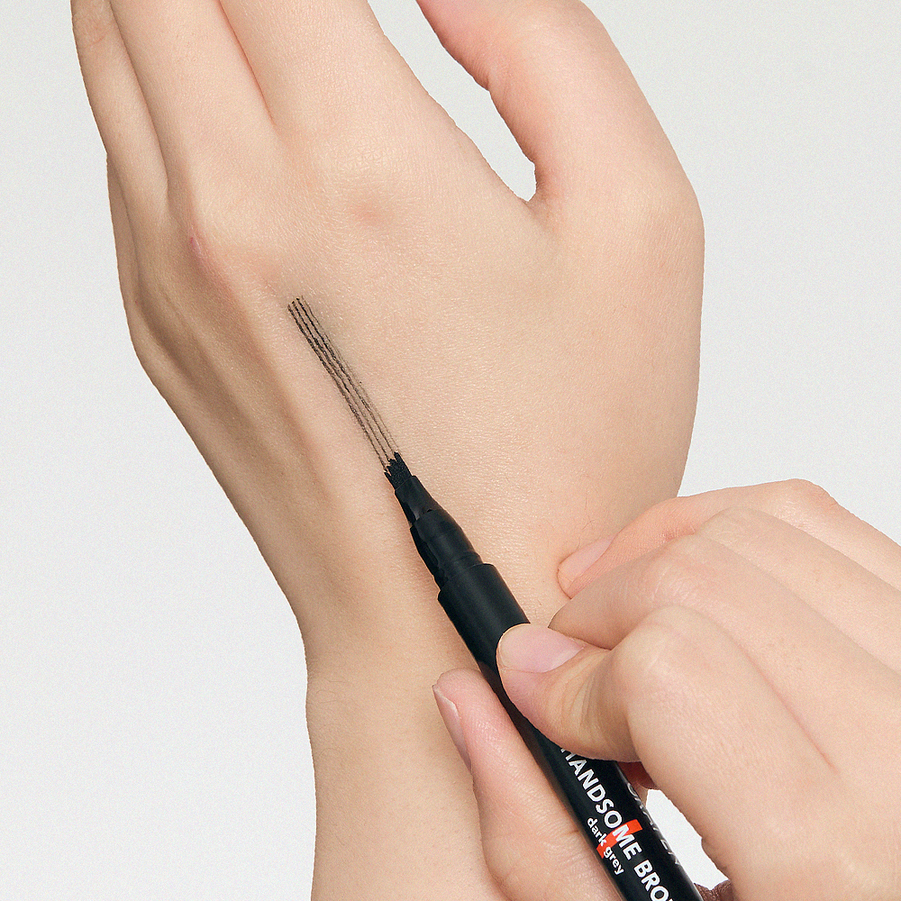 Décris l'image en français : GRAFEN  Handsome Tattoo Brow 0.8g, stylo tatouage sourcils sur la main, application visuelle.