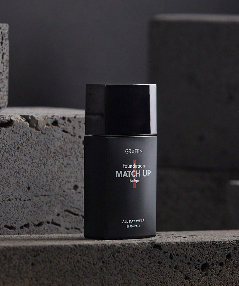 GRAFEN  Match Up Foundation 40ml, flacon noir sur pierre grise, studio beauté en arrière-plan sombre.