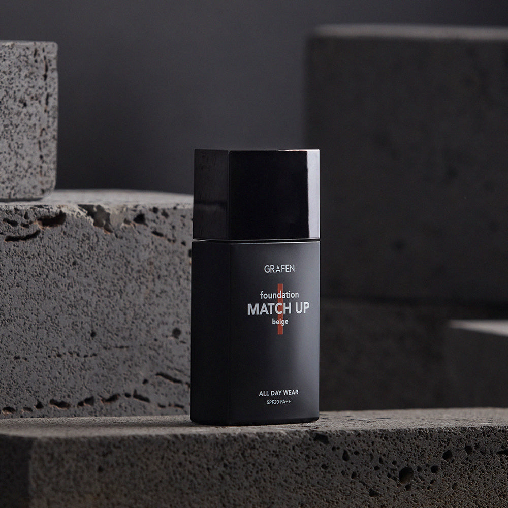 GRAFEN  Match Up Foundation 40ml, flacon noir sur pierre grise, studio beauté en arrière-plan sombre.