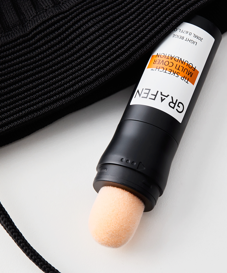GRAFEN Tip Sketch™ Multi-Cover Foundation 20ml, tube maquillage sur tissu noir et fond blanc, produit de la marque