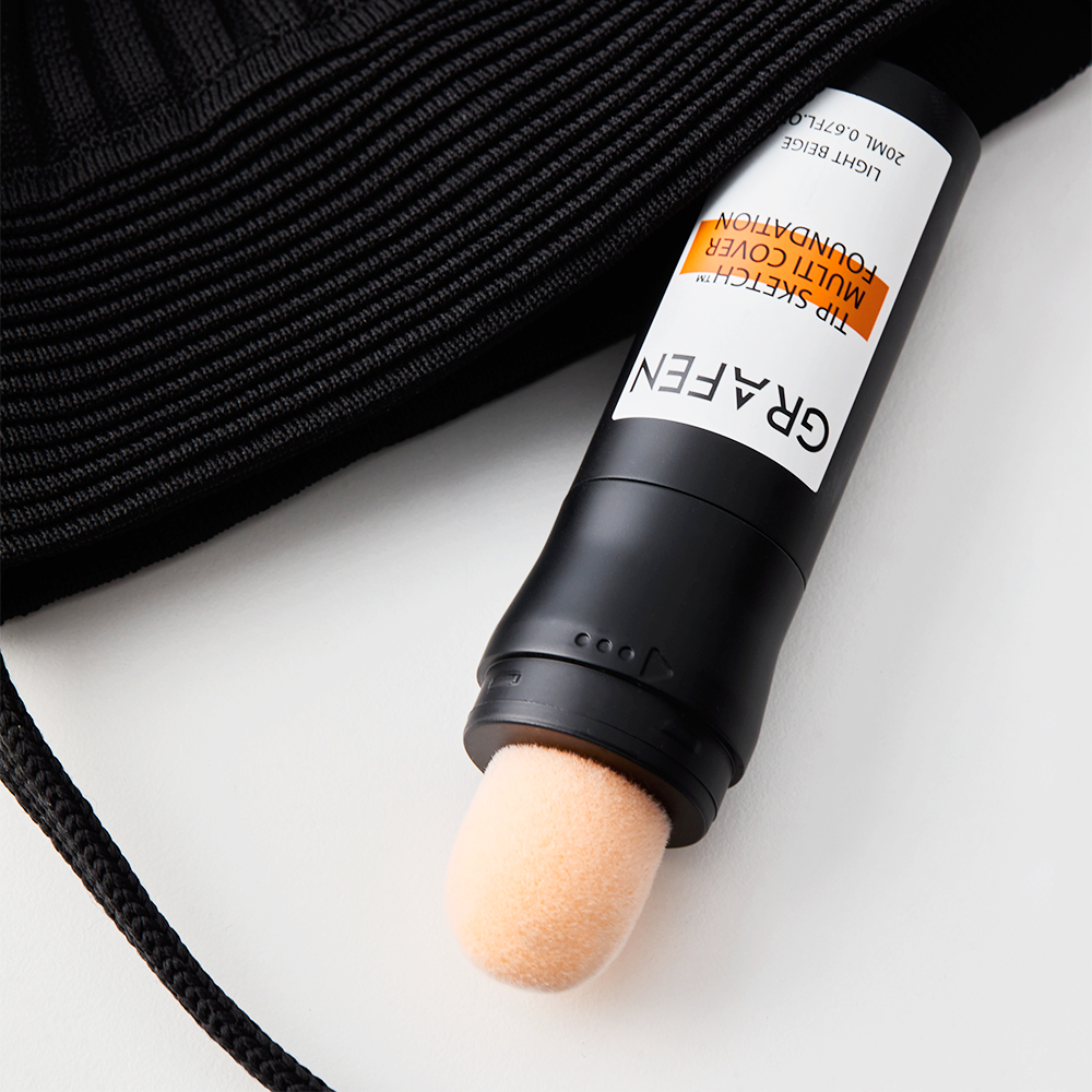GRAFEN Tip Sketch™ Multi-Cover Foundation 20ml, tube maquillage sur tissu noir et fond blanc, produit de la marque