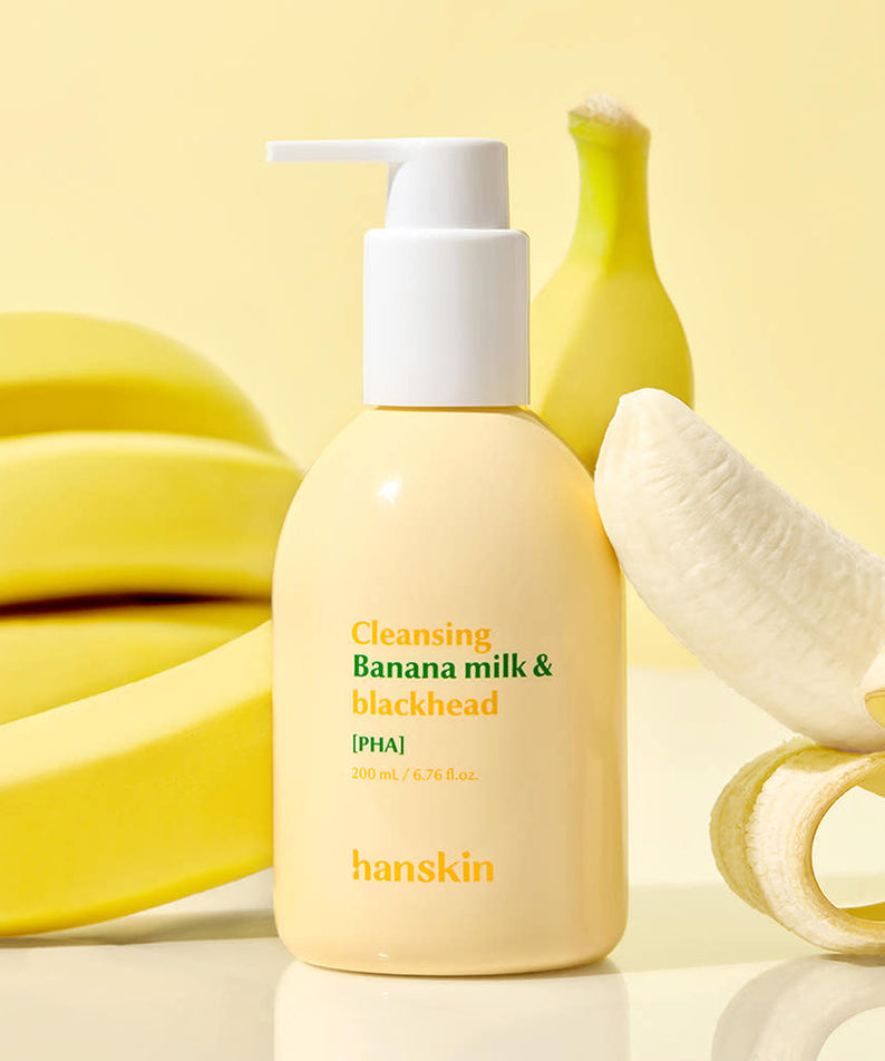 Décris l'image en français : HANSKIN Cleansing Banana Milk & Blackhead PHA 200ml sur fond jaune avec bananes et pompe.