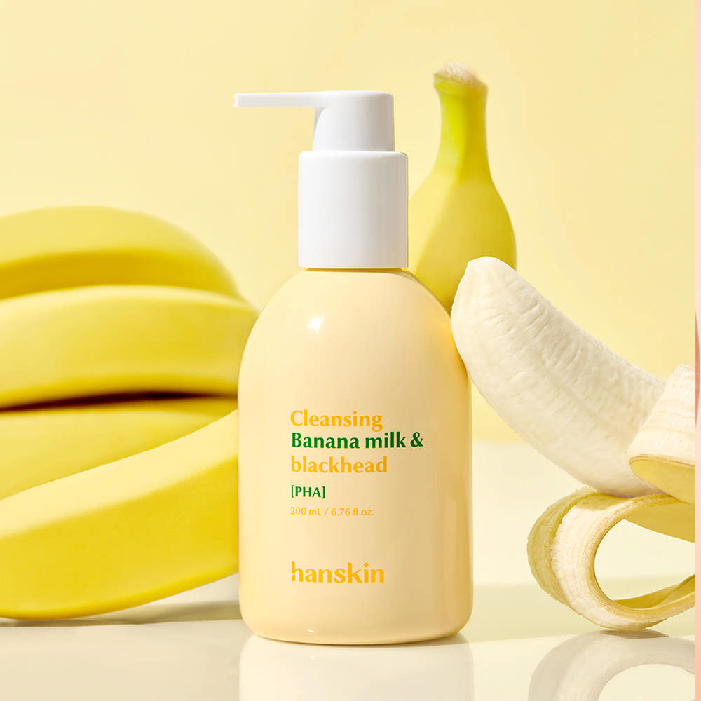 Décris l'image en français : HANSKIN Cleansing Banana Milk & Blackhead PHA 200ml sur fond jaune avec bananes et pompe.
