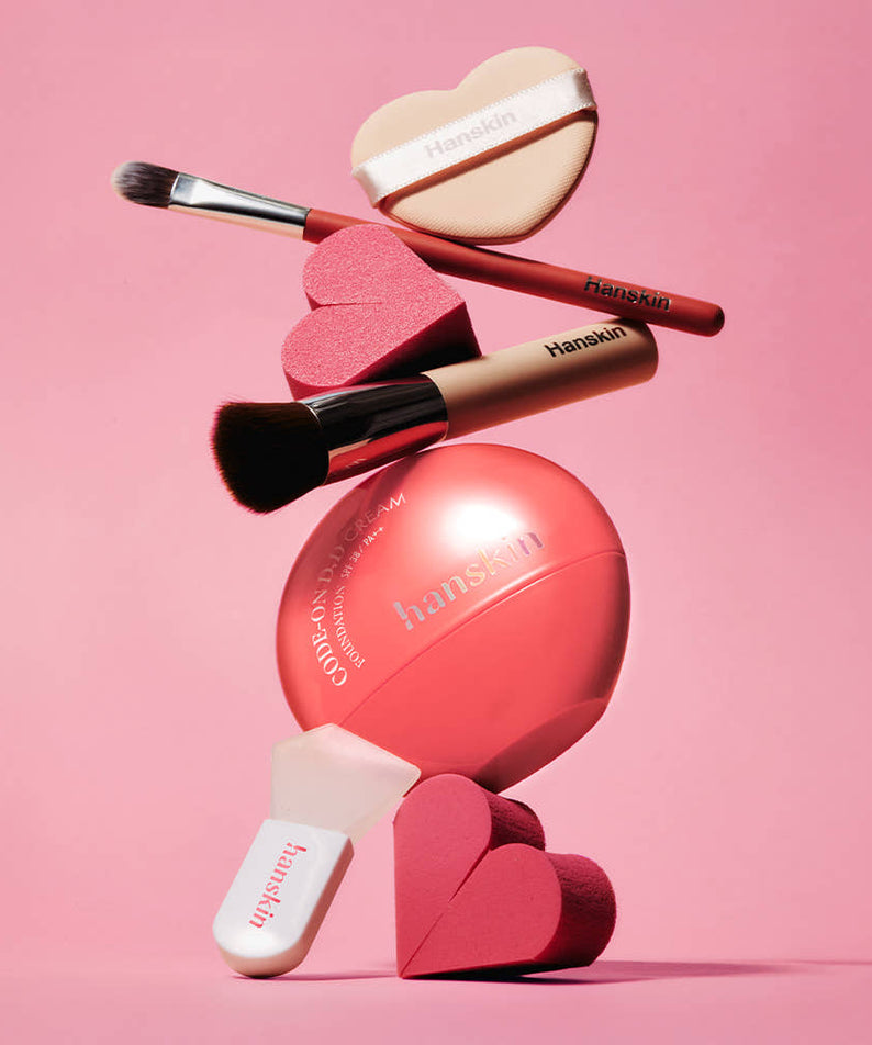 HANSKIN Code On DD Cream Foundation 35ml de HANSKIN sur fond rose, maquillage et accessoires visibles