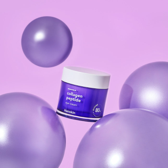 Décris l'image en français : HANSKIN Large Capacity Collagen Peptide Eye Cream 80ml, pot collagène près de sphères violettes.