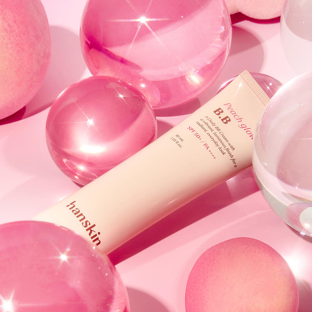 HANSKIN Peach Glow BB Cream 30ml de HANSKIN sur fond rose avec perles et cœurs, effet glow lumineux