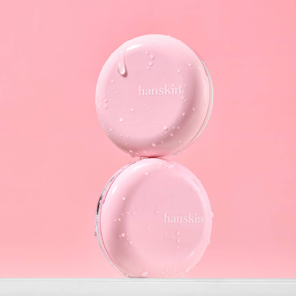 HANSKIN Pink Moisturizing Tone-Up Sun Cushion 8g, produit crème rose sur fond rose, gouttes de texture, marque visible