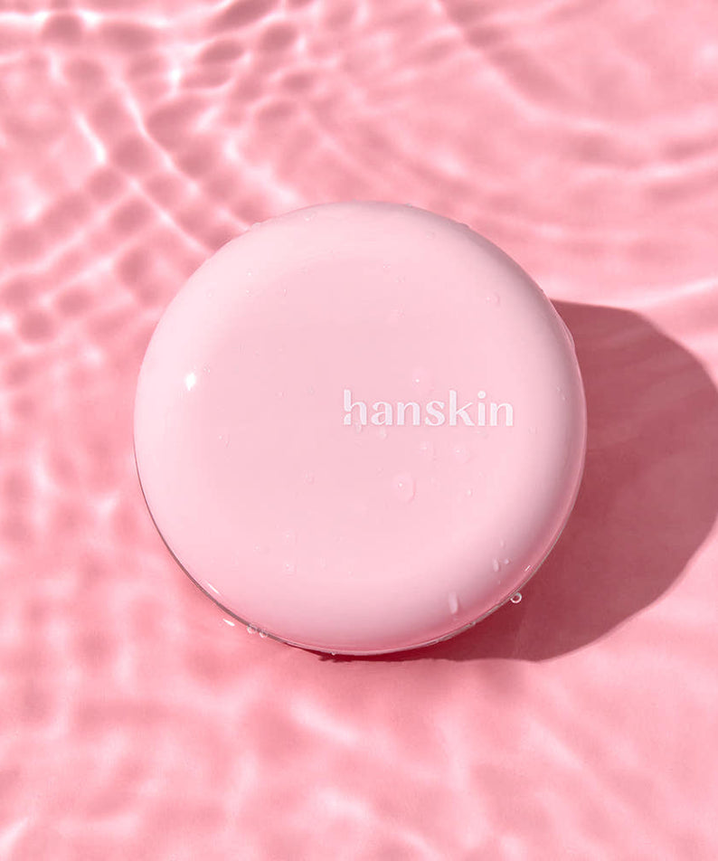 HANSKIN Pink Moisturizing Tone-Up Sun Cushion 8g de HANSKIN, coussin rose sur fond rose ondulé, flacon rond visible.