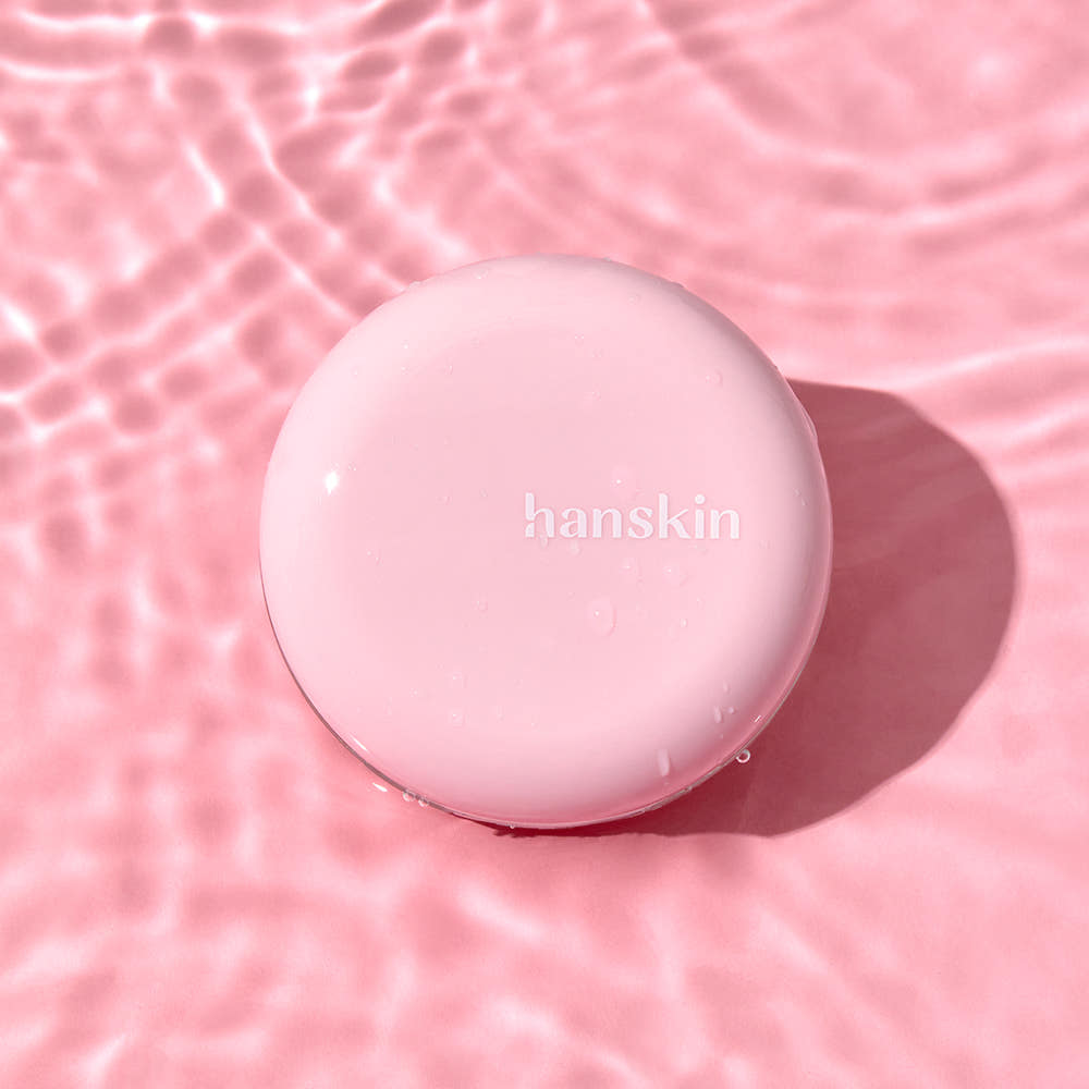 HANSKIN Pink Moisturizing Tone-Up Sun Cushion 8g de HANSKIN, coussin rose sur fond rose ondulé, flacon rond visible.