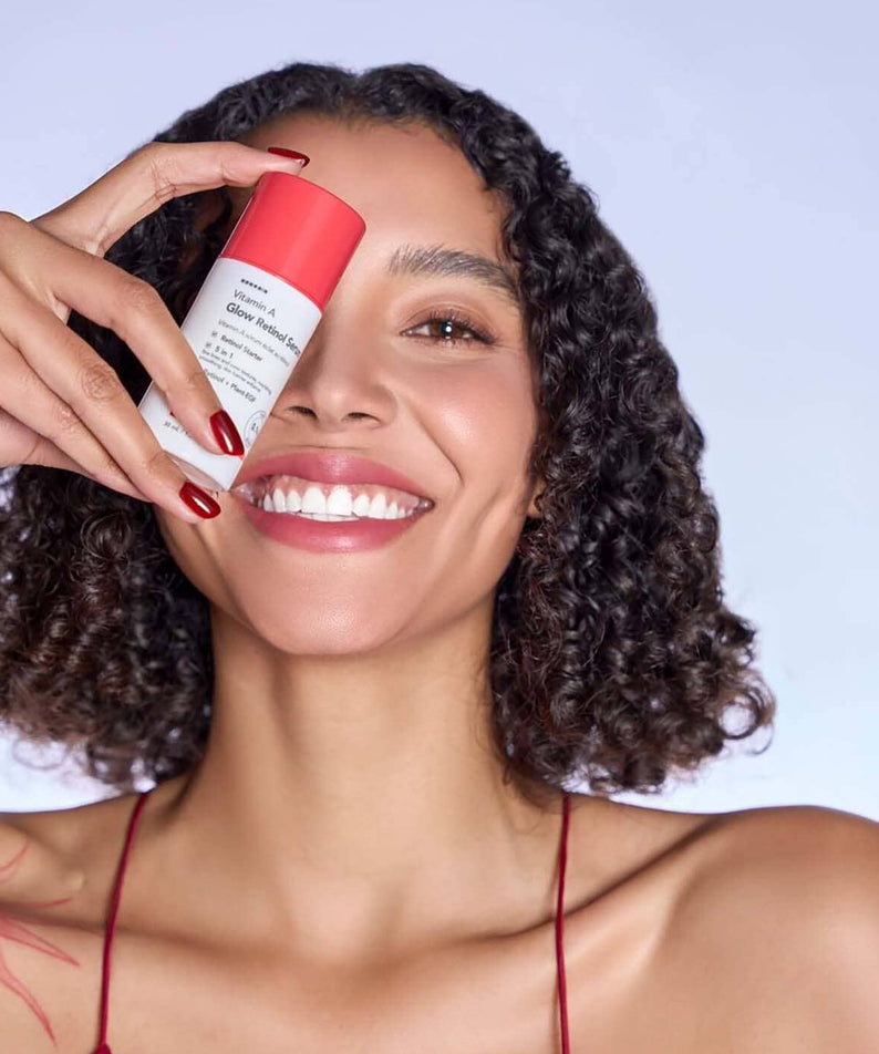 HANSKIN Vitamin A Glow Retinol Serum 30ml de HANSKIN, sur fond bleu clair, main tenant le flacon devant un visage souriant
