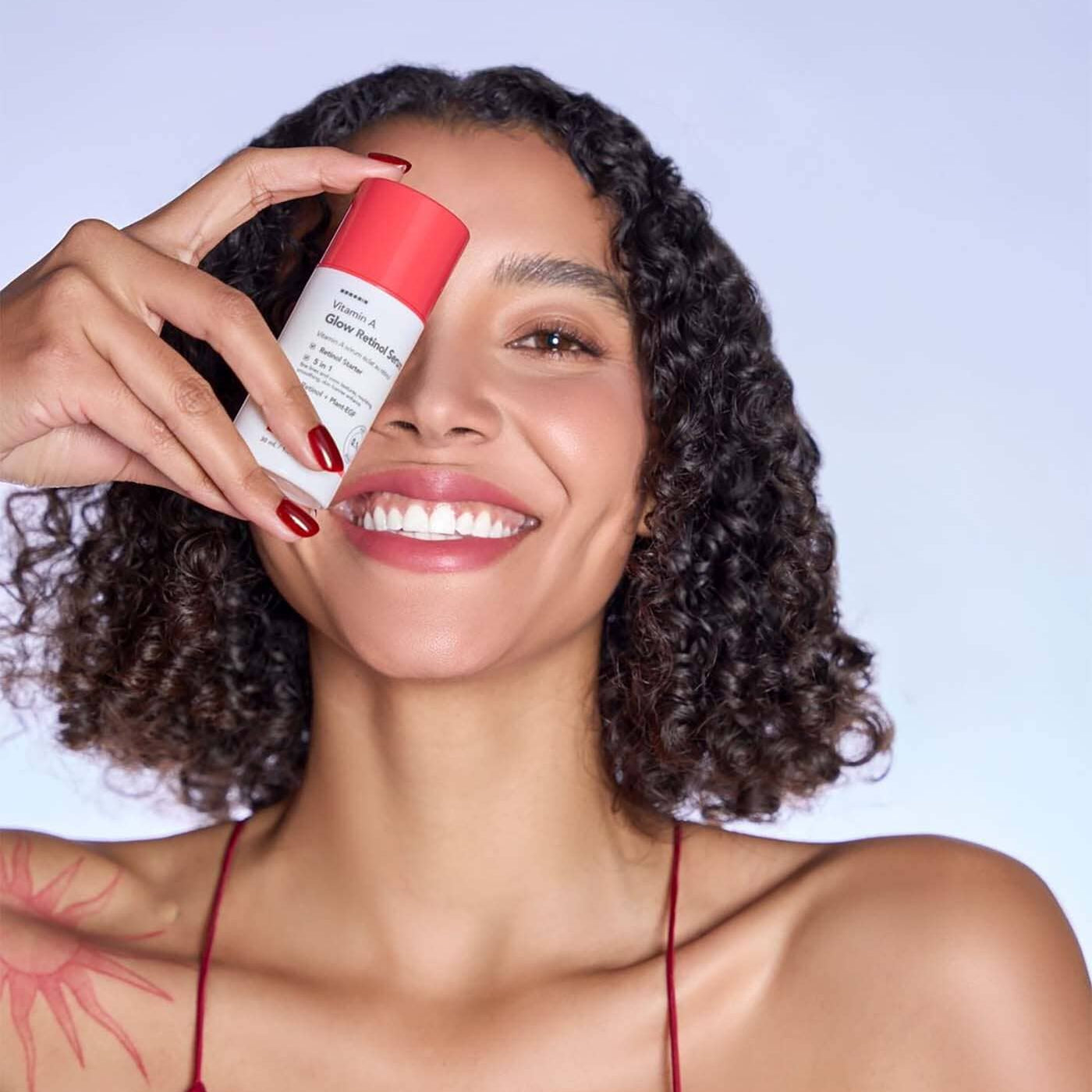 HANSKIN Vitamin A Glow Retinol Serum 30ml de HANSKIN, sur fond bleu clair, main tenant le flacon devant un visage souriant