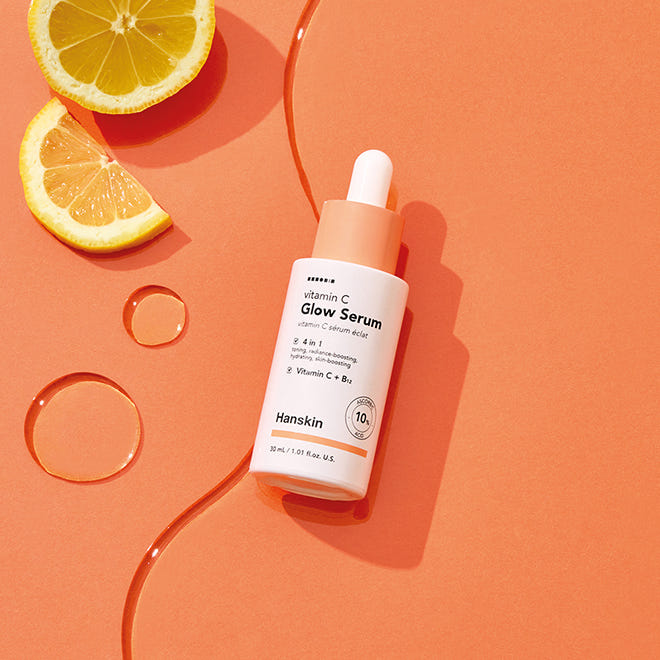 HANSKIN Vitamin C Glow Serum 30ml, sérum à la vitamine C sur fond orange avec tranches de citron et flacon HANSKIN