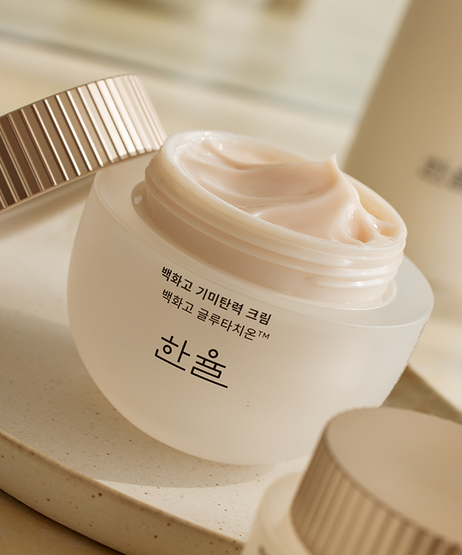 Décris l'image en français : HANYUL Baekhwago Gimitanryuk Eye Cream 25ml, crème sous pot, sur fond beige.