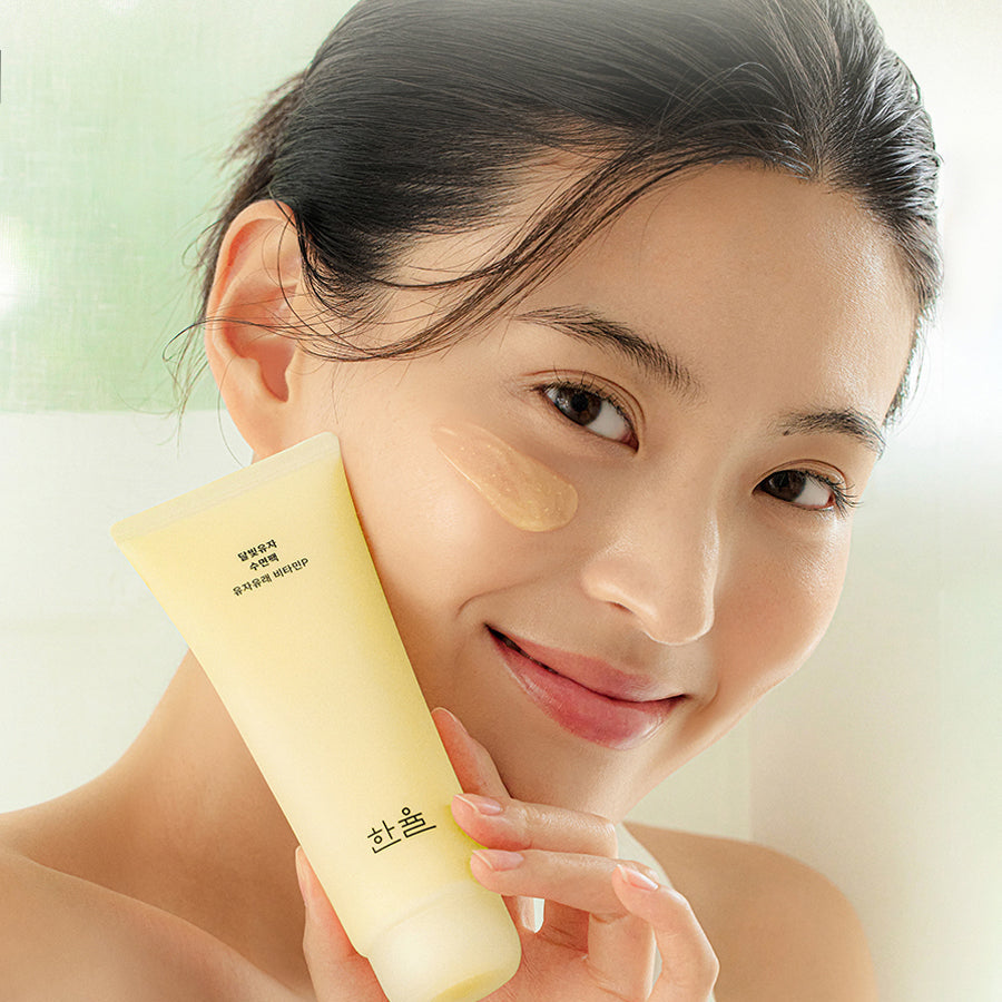 HANYUL Moonlight Yuja Sleeping Pack 100ml de HANYUL, sur visage féminin tenant le tube, ambiance spa lumineuse
