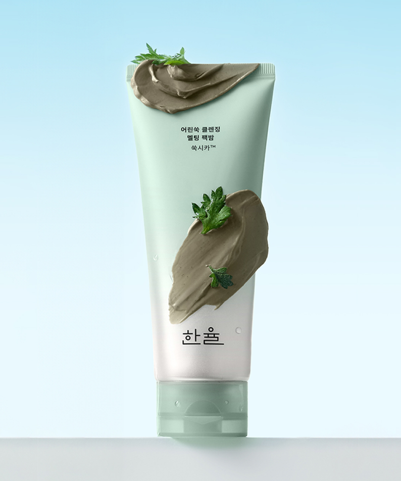 HANYUL Young Artemisia Cleansing Pack Balm 100g : tube de baume nettoyant sur fond bleu, textures d’armoise et herbes vertes.